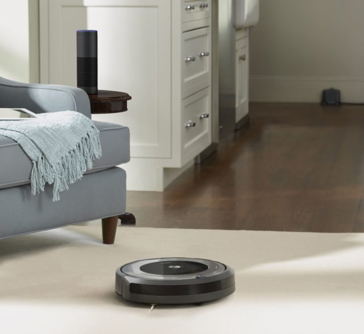 The Roomba vacuums on the carpeted section of a room.