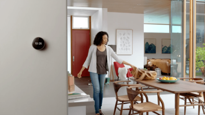 A woman arriving home and the Nest thermostat lights up which demonstrates how Nest's "farsight" feature works.