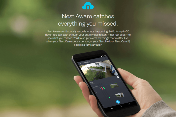 A human hand holding a smartphone, showing the Nest Aware feature of the Nest Cams.