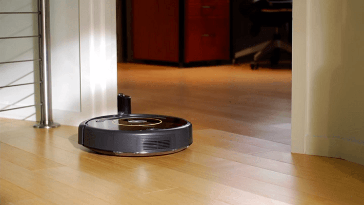 The Roomba vacuums on a hardwood floor.